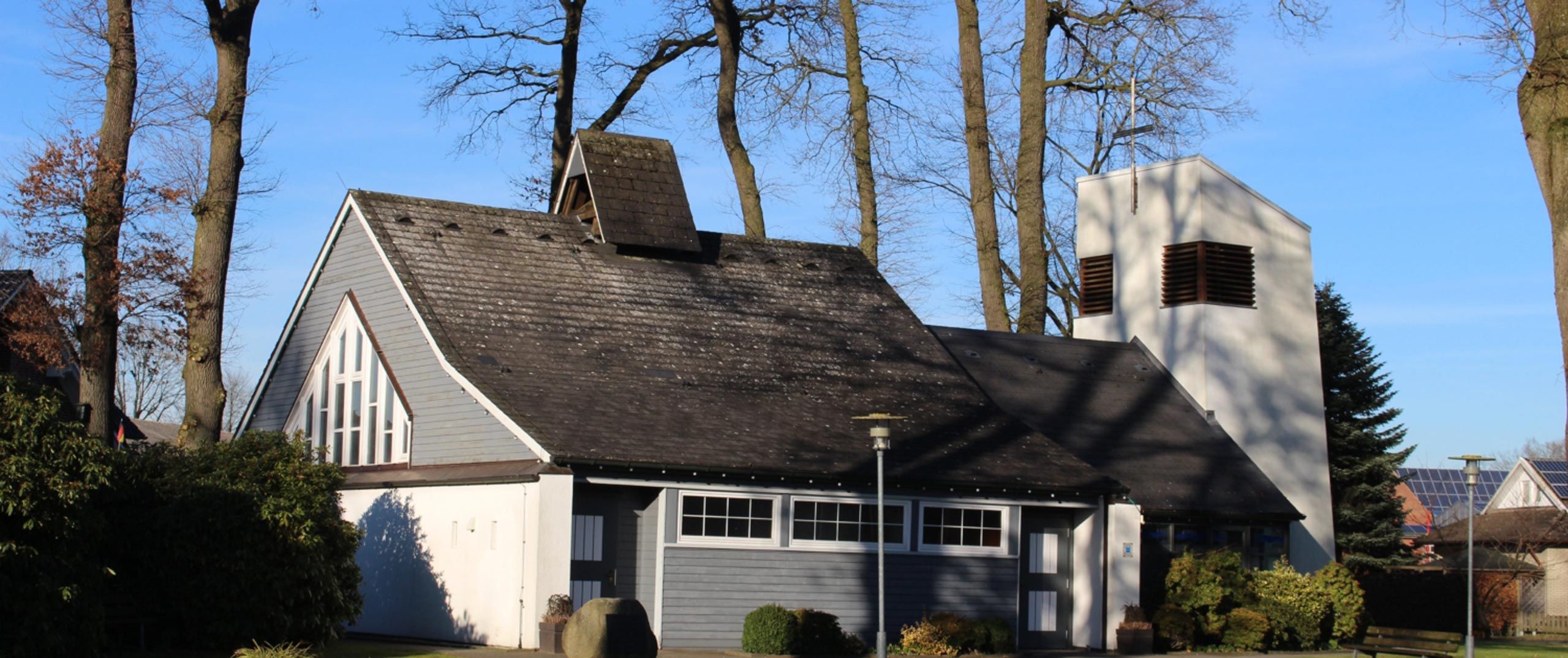 Moderne Kirche, weiß-grau vertäfelt mit dunkelgrauem Dach